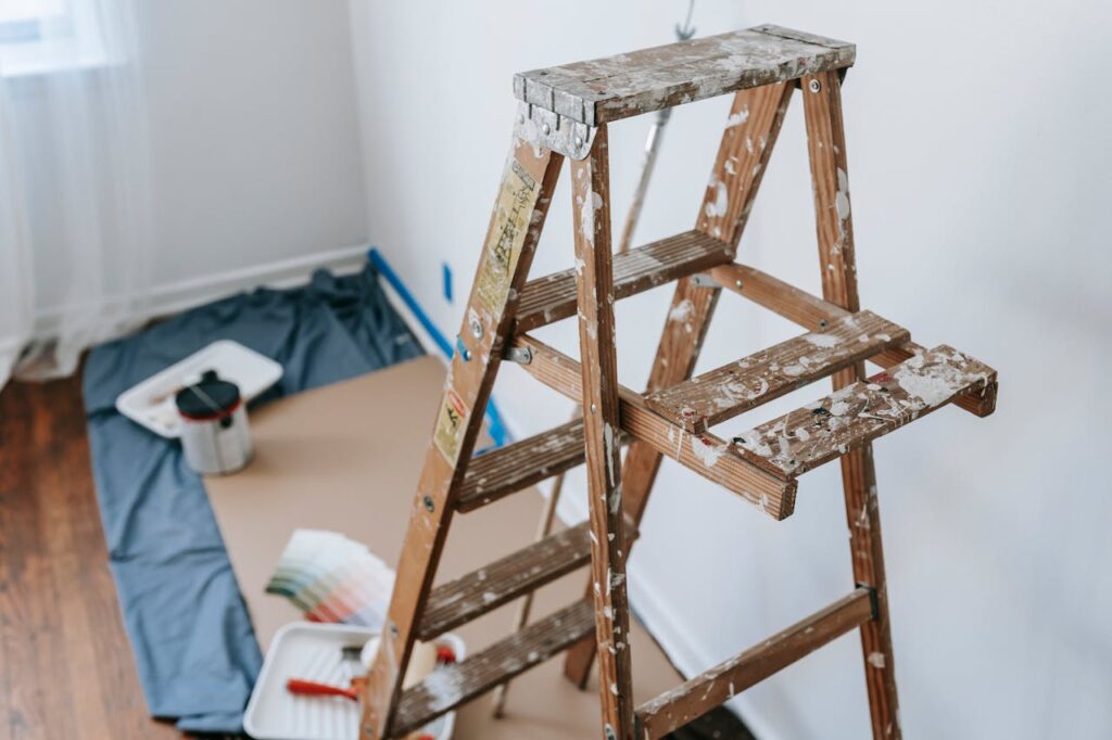 A messy stepladder and painting tools set up for a home interior renovation project.